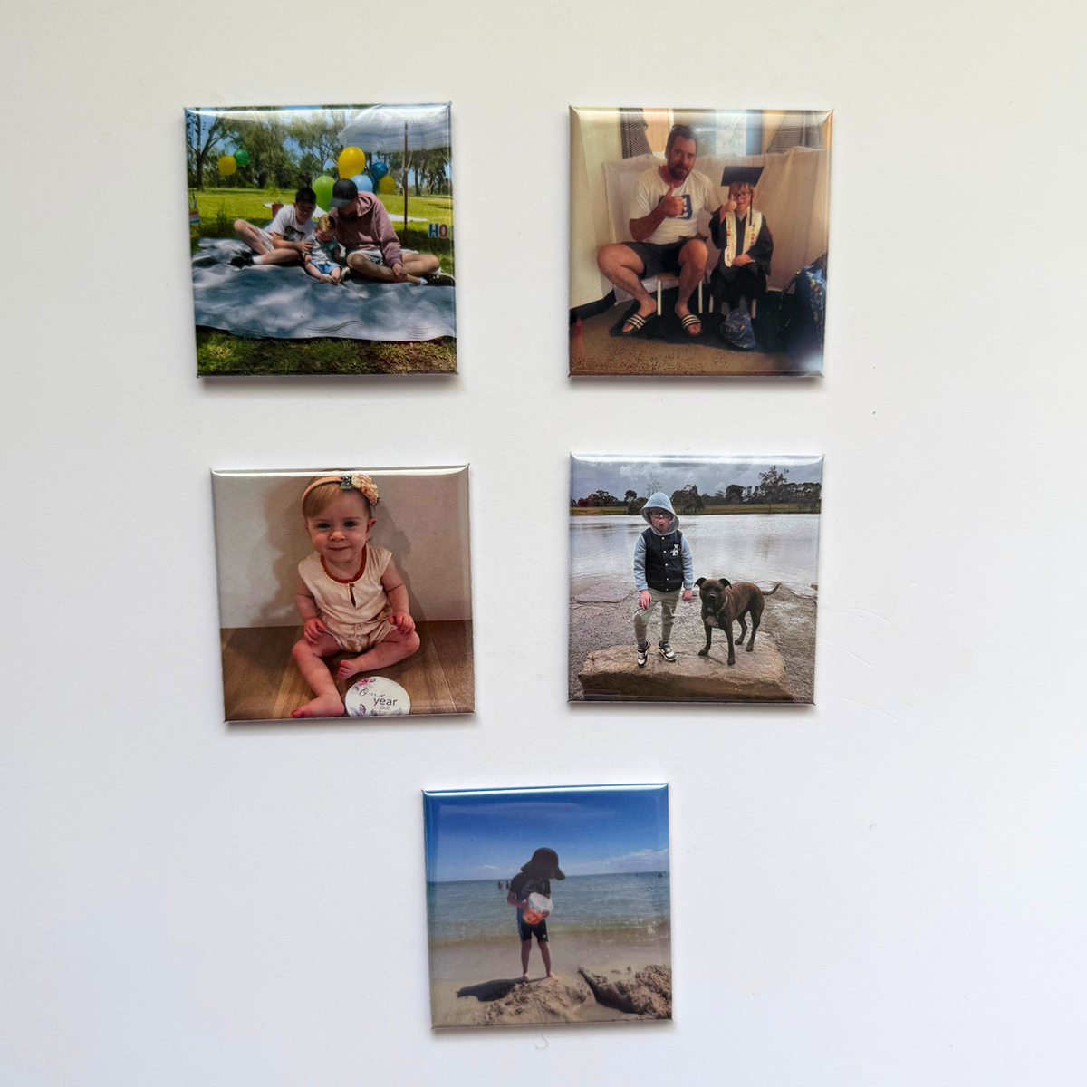 Five custom 50mm photo magnets with family milestone photos displayed on a wall