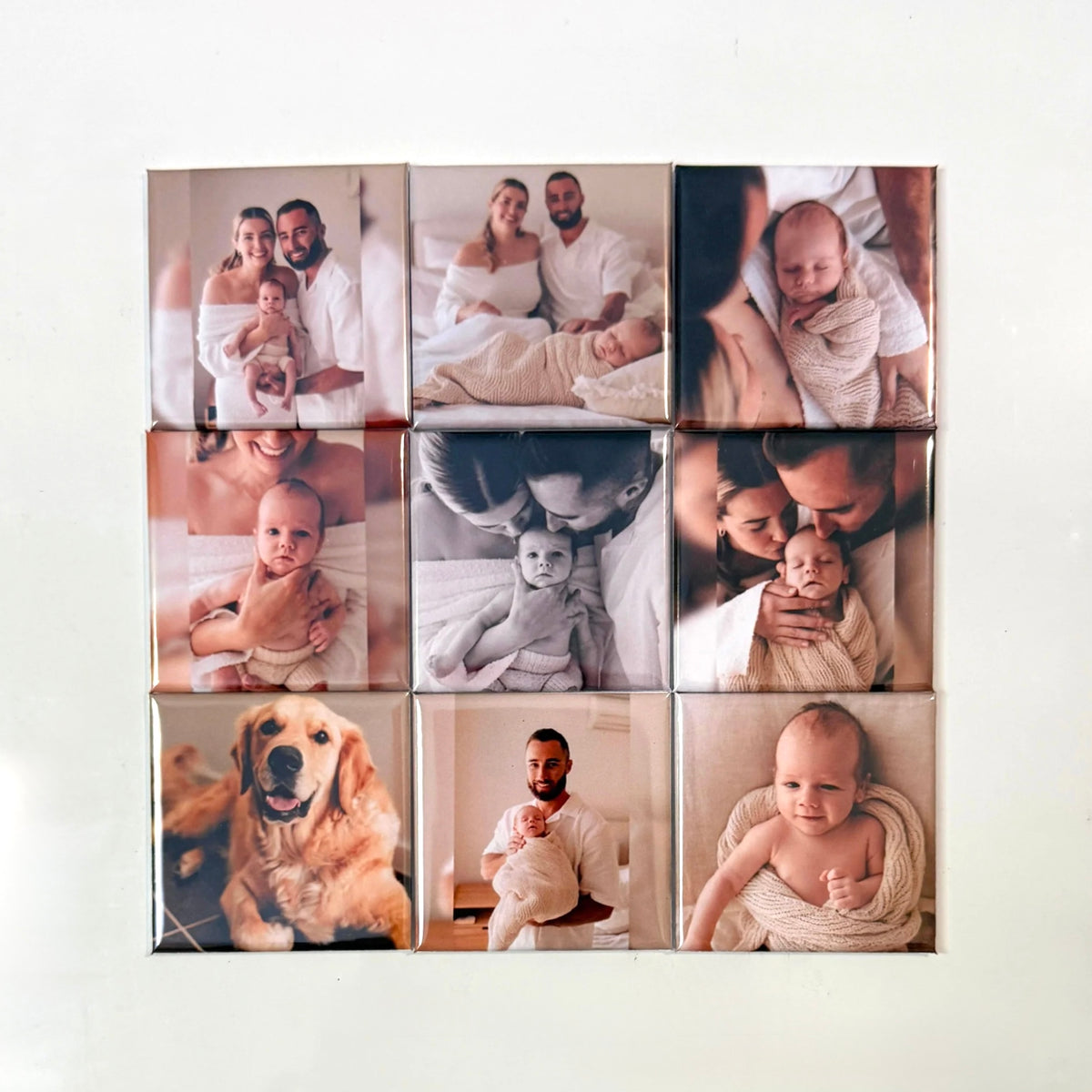 A 3x3 grid of square custom photo tiles mounted on a light beige wall. The photos depict various family and pet scenes, including babies, adults, a golden retriever, and black-and-white moments, with a soft shadow around the tiles.