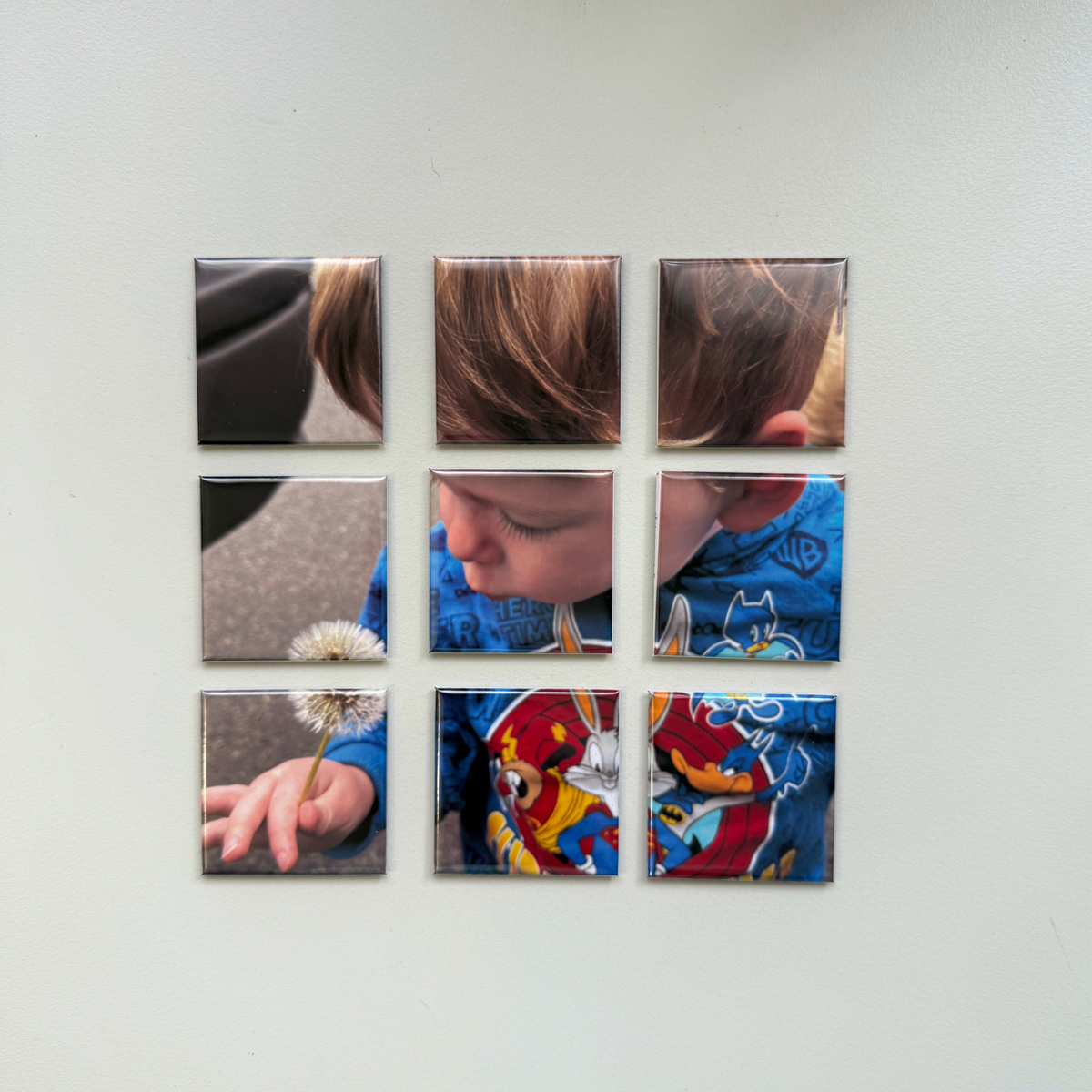 9-piece custom photo puzzle magnets on wall showing child blowing dandelion — personalised fridge magnet set handmade in Melbourne Australia