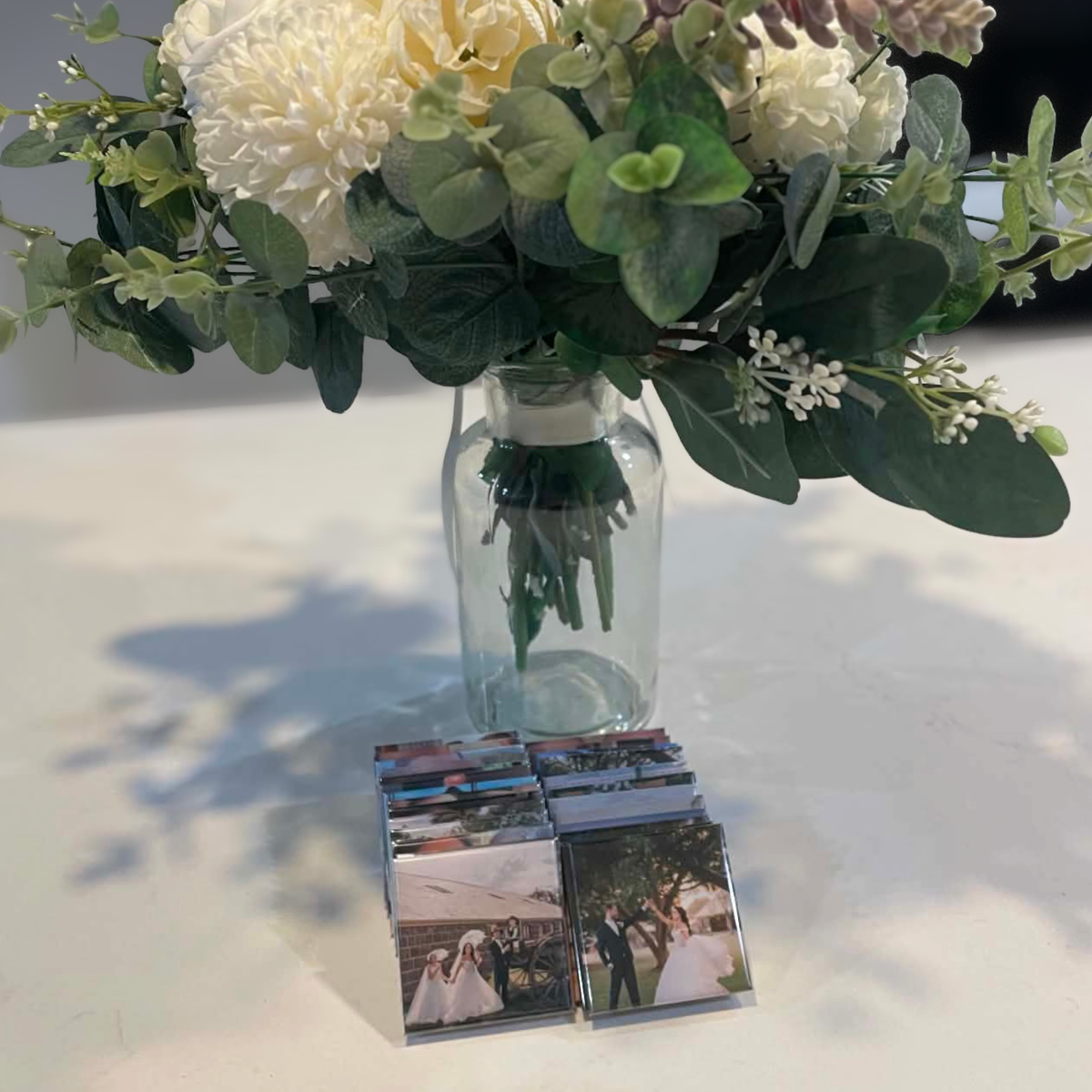 Custom wedding photo magnets displayed beside floral centrepiece at reception table — personalised wedding keepsakes handmade in Melbourne Australia